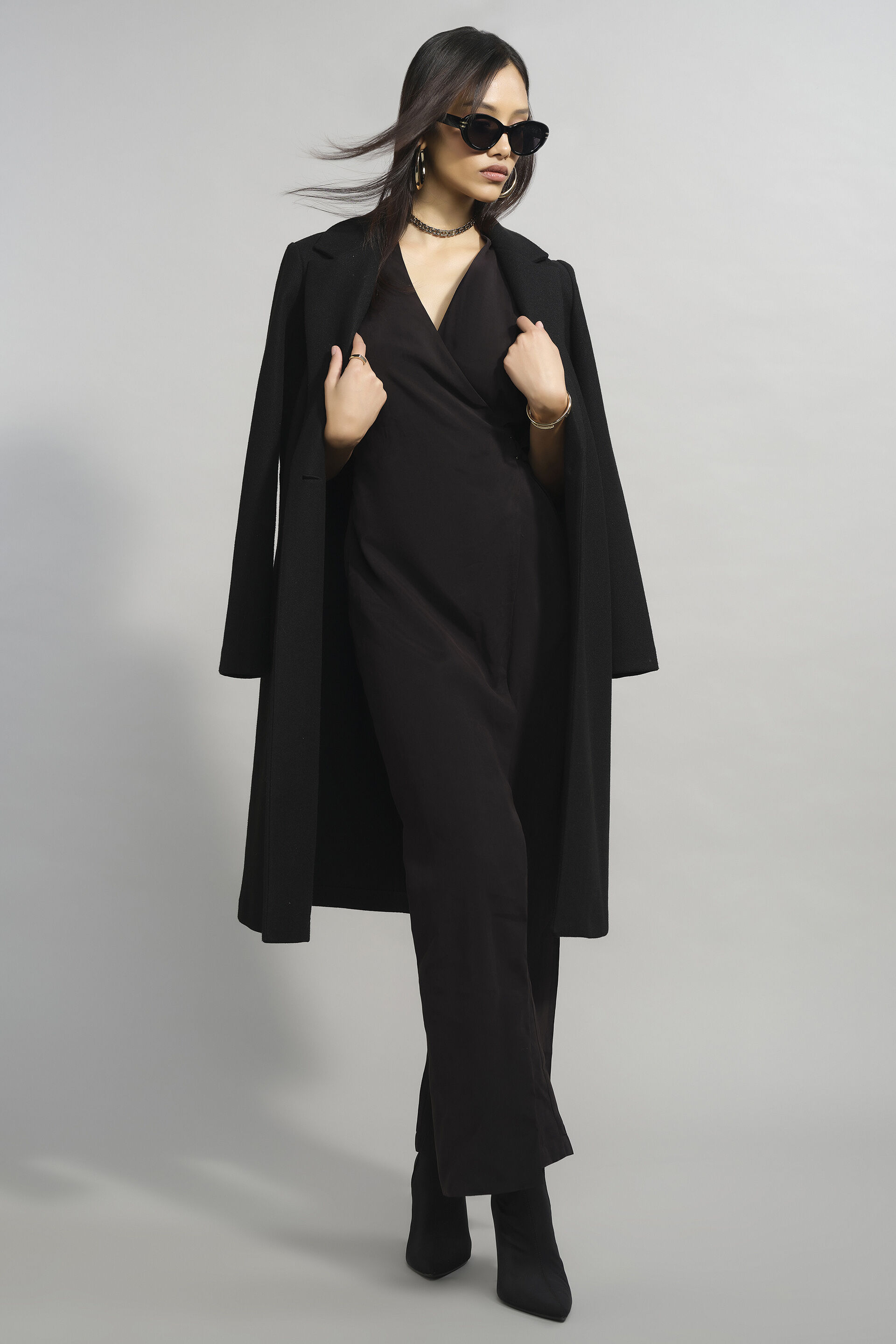 Woman in black trench coat over festive jumpsuit